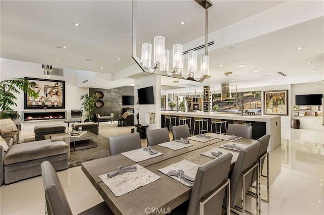 dining room featuring a fireplace, an inviting chandelier, and light tile patterned floors