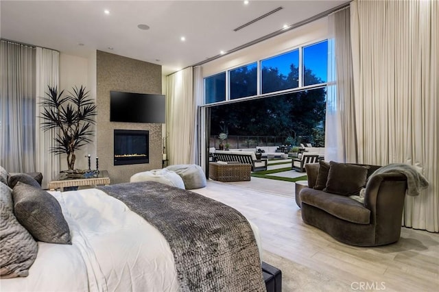 bedroom with light hardwood / wood-style flooring and a fireplace