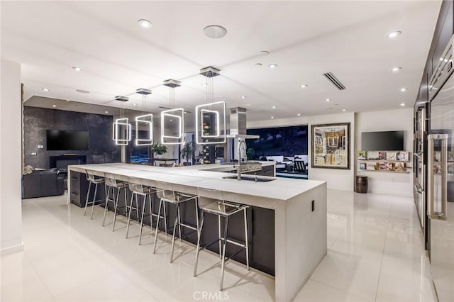 kitchen featuring hanging light fixtures, a breakfast bar, a spacious island, sink, and light tile patterned flooring