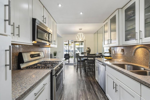 kitchen featuring stainless steel appliances, sink, decorative light fixtures, white cabinetry, and decorative backsplash