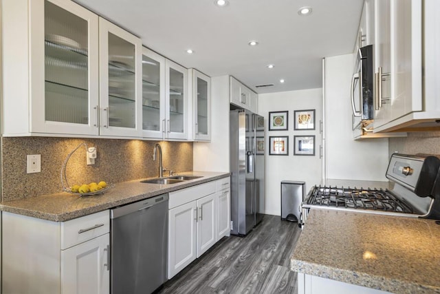 kitchen with appliances with stainless steel finishes, dark wood-type flooring, light stone counters, sink, and white cabinetry