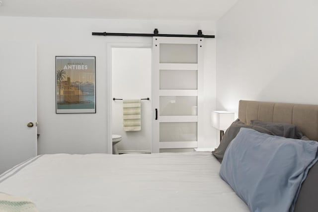 bedroom featuring ensuite bath and a barn door