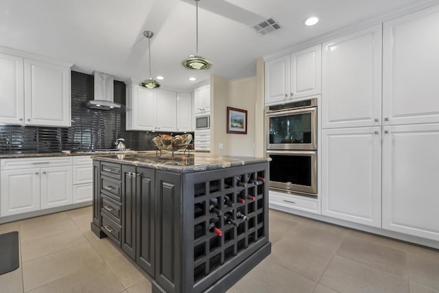 kitchen with white cabinetry, wall chimney exhaust hood, tasteful backsplash, a kitchen island, and double oven