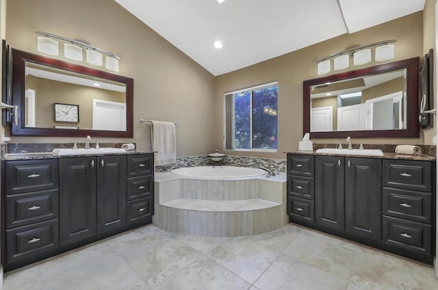 bathroom featuring tiled bath, lofted ceiling, and vanity