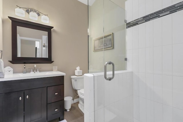 bathroom with a shower with door, vanity, and toilet