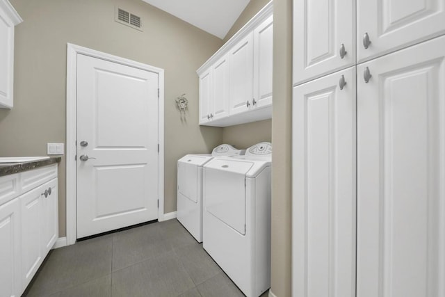 clothes washing area featuring cabinets, tile patterned flooring, and washing machine and clothes dryer