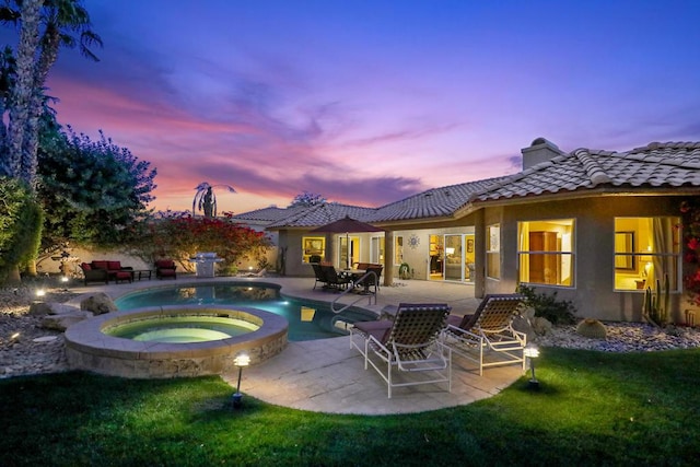 pool at dusk featuring an in ground hot tub and a patio area