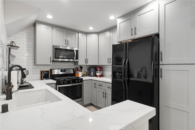 kitchen with stainless steel appliances, sink, tasteful backsplash, and light stone countertops