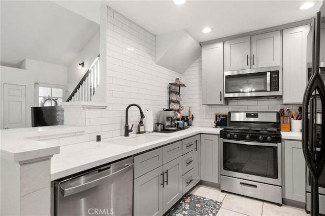 kitchen with stainless steel appliances, gray cabinets, backsplash, and sink