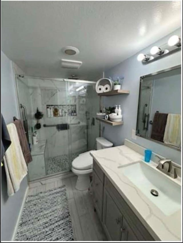 bathroom with vanity, a shower with door, and toilet