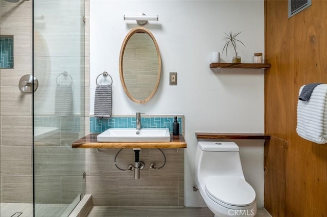 bathroom featuring sink, a tile shower, and toilet