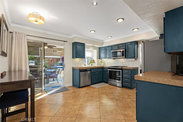 kitchen with stainless steel appliances, blue cabinetry, crown molding, a healthy amount of sunlight, and backsplash