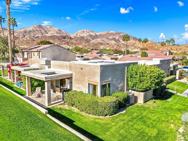 rear view of property with central air condition unit, a mountain view, and a lawn