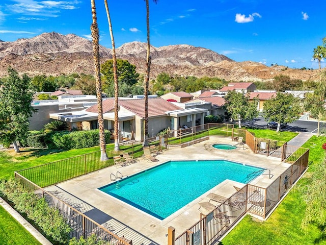 view of pool featuring a patio, a hot tub, a mountain view, and a lawn