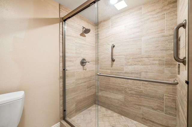 bathroom featuring toilet and a shower with door