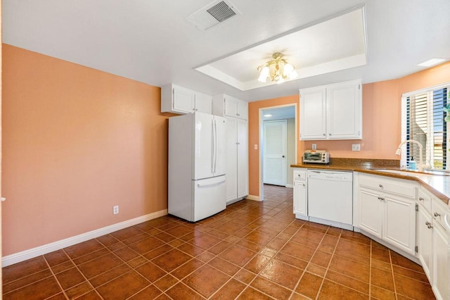 kitchen featuring white appliances, a raised ceiling, dark tile patterned flooring, white cabinetry, and sink