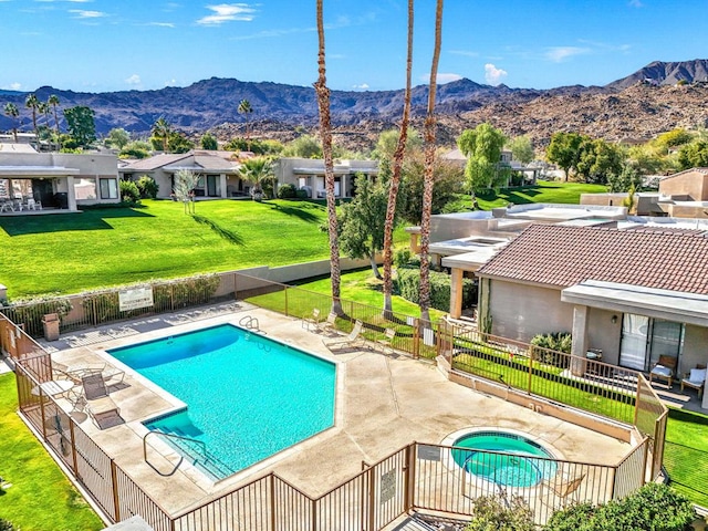 view of swimming pool with a community hot tub, a patio, a mountain view, and a lawn