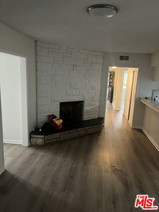 unfurnished living room featuring wood-type flooring and a stone fireplace