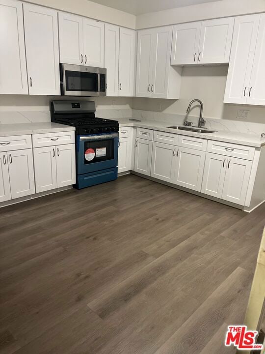 kitchen featuring appliances with stainless steel finishes, dark hardwood / wood-style floors, white cabinets, and sink