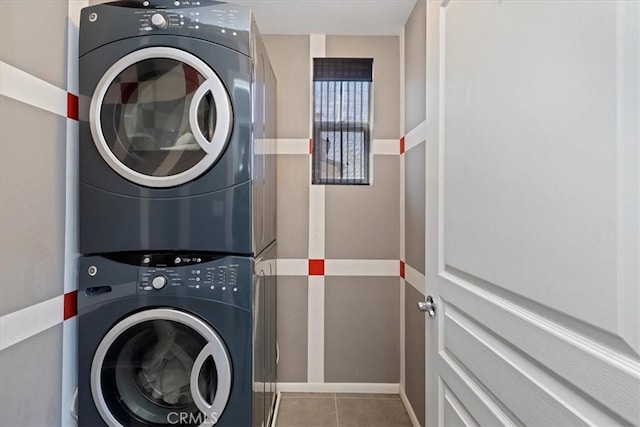 laundry room featuring stacked washing maching and dryer and light tile patterned floors