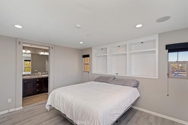 bedroom with multiple windows, light hardwood / wood-style flooring, and connected bathroom