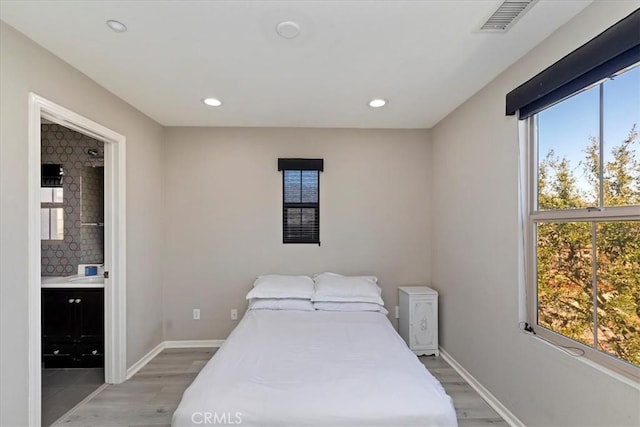 bedroom with light hardwood / wood-style floors and ensuite bathroom