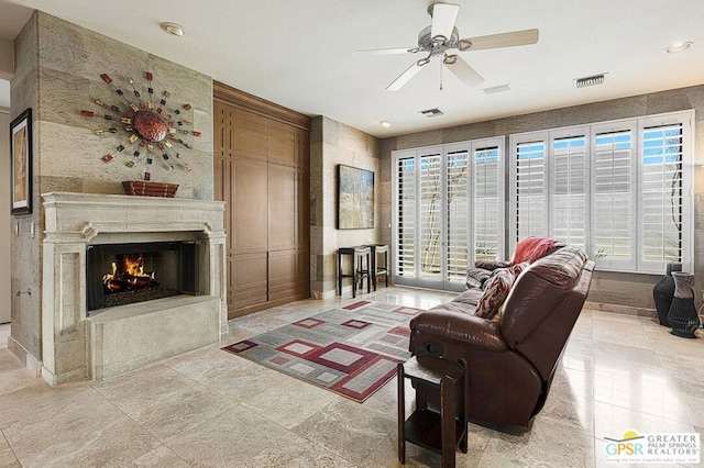 living room featuring a high end fireplace, ceiling fan, and plenty of natural light