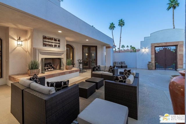 patio terrace at dusk with french doors and an outdoor living space with a fireplace