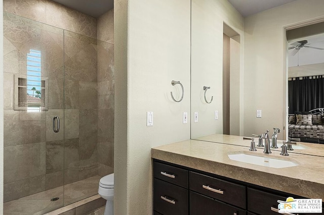 bathroom with toilet, ceiling fan, a shower with shower door, and vanity