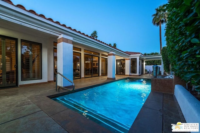 pool at dusk featuring a patio