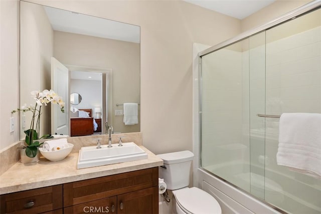 full bath with ensuite bath, shower / bath combination with glass door, vanity, and toilet