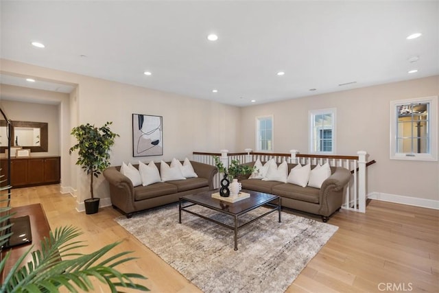 living area with baseboards, light wood finished floors, and recessed lighting