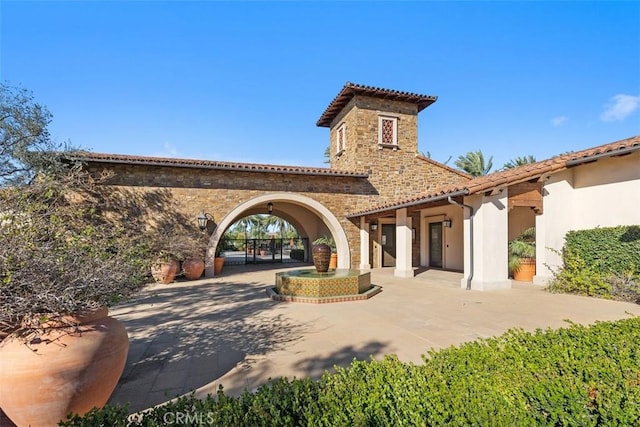 rear view of property with stone siding and a patio