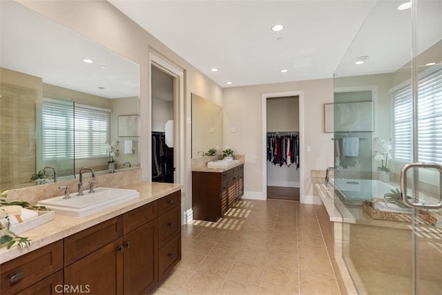 bathroom featuring baseboards, tile patterned flooring, a sink, and a healthy amount of sunlight