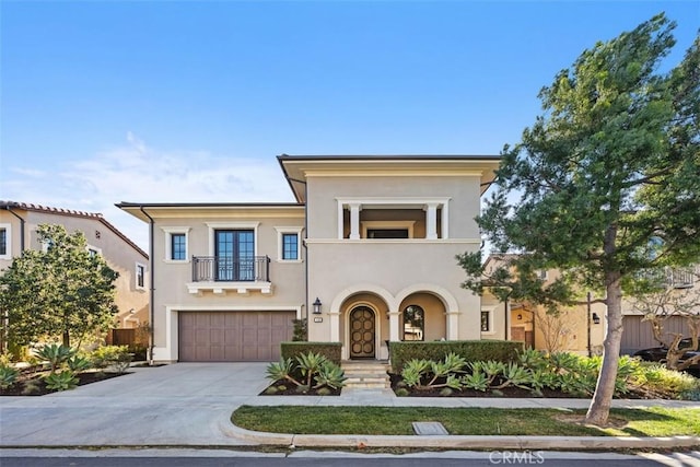 view of front of property with a garage, driveway, a balcony, and stucco siding