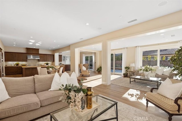 living room featuring light wood-type flooring, visible vents, and recessed lighting