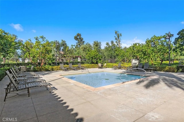 community pool with fence and a patio