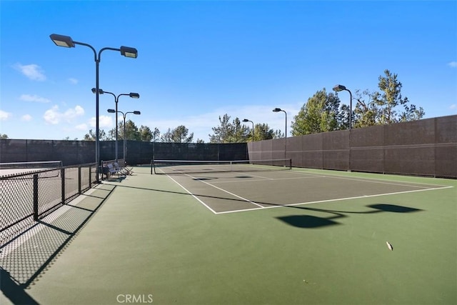 view of tennis court featuring community basketball court and fence