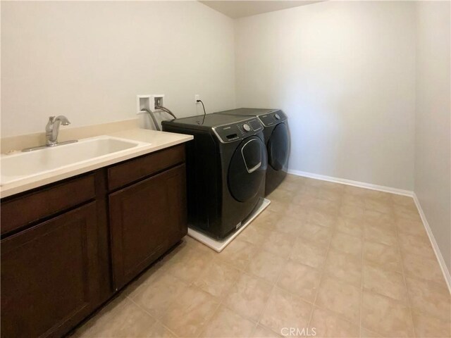 clothes washing area featuring sink, cabinets, and washer and dryer