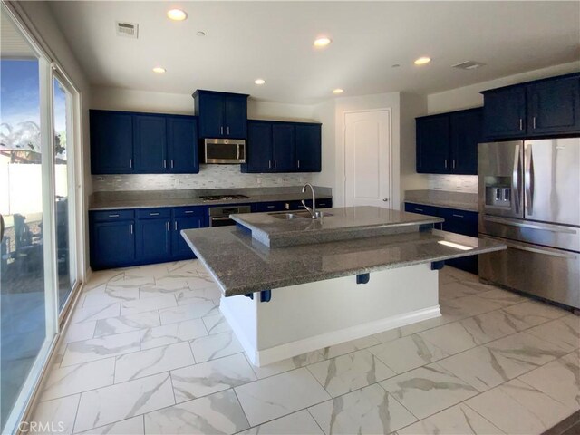 kitchen featuring a kitchen island with sink, blue cabinetry, a breakfast bar area, appliances with stainless steel finishes, and sink