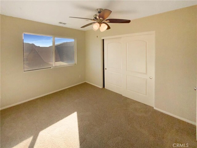 unfurnished bedroom with ceiling fan, a closet, and carpet floors