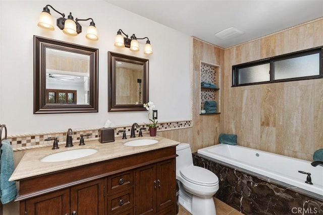 bathroom with tile patterned floors, tiled tub, toilet, and vanity