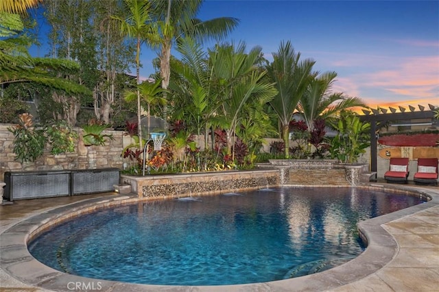 pool at dusk featuring pool water feature, a pergola, and a patio