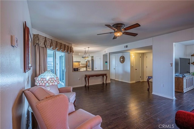 living room with ceiling fan with notable chandelier and dark wood-type flooring