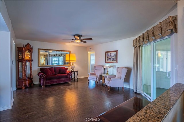 living room featuring ceiling fan, a wealth of natural light, and dark wood-type flooring