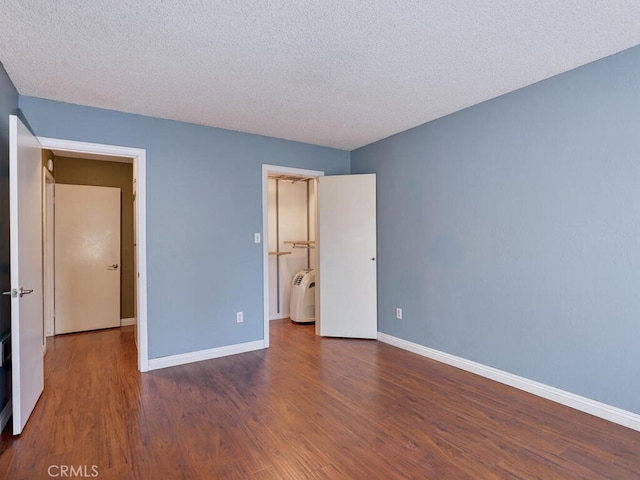 unfurnished bedroom with a textured ceiling, dark hardwood / wood-style flooring, and washer / clothes dryer