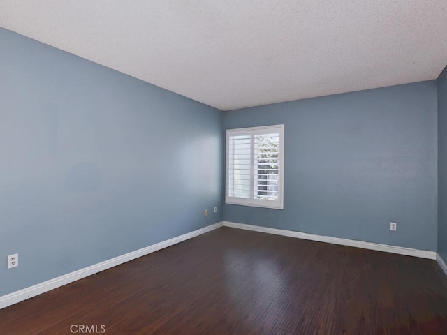 empty room featuring dark hardwood / wood-style flooring and a textured ceiling