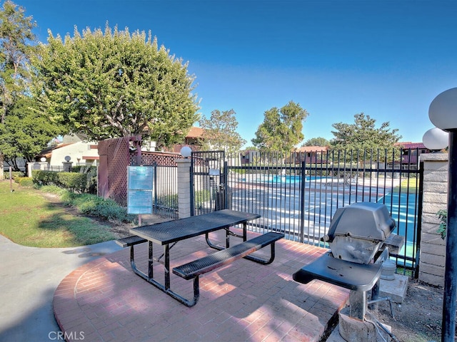 view of patio with a community pool and area for grilling