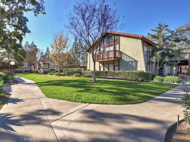 view of side of property featuring a lawn and a balcony