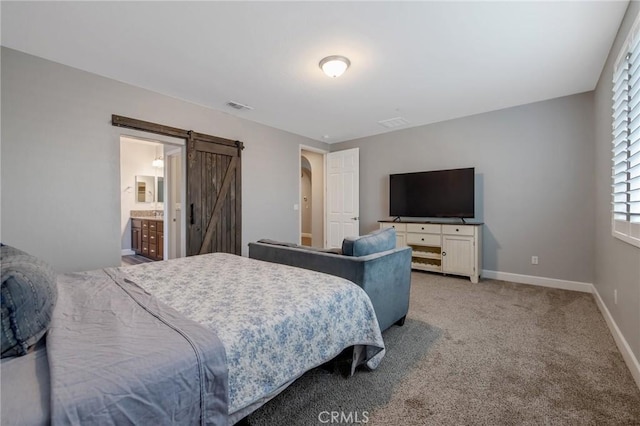 bedroom featuring ensuite bathroom, a barn door, and carpet floors